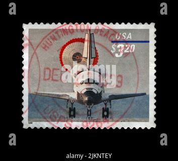 Space Shuttle with parachute Landing, USA, circa 1998. vintage postal stamp isolated on black background. Stock Photo