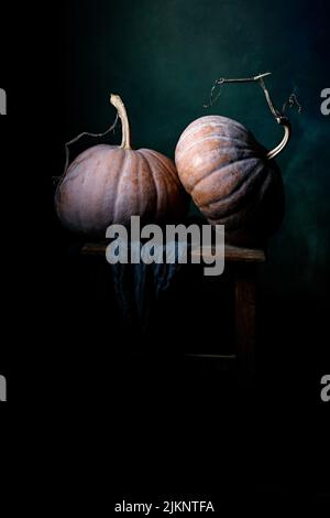A vertical closeup of the pumpkins on the wooden table on dark background. Still life. Stock Photo