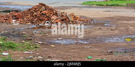 A dirty road with a bunch of broken bricks and trash in zimbabwe Stock Photo
