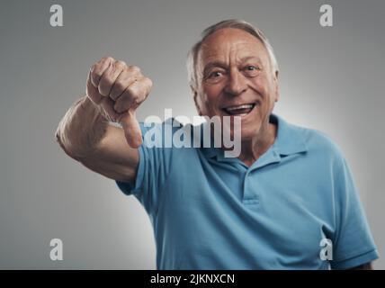 Id give that product a thumbs down definitely. a happy older man giving the thumbs down in a studio against a grey background. Stock Photo