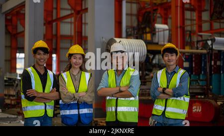 Yound worker and Expertise and knowledge in heavy industry plants. A happy proud senior and young factory worker stands with arms crossed Partner indu Stock Photo