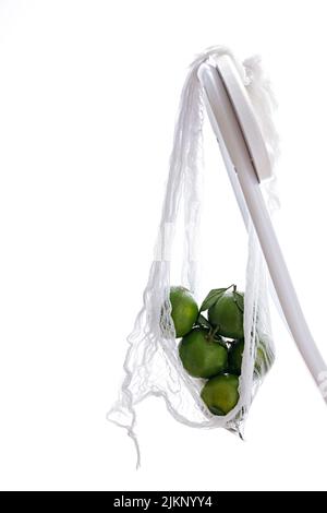 a vertical shot of green lemons in bag on a white background Stock Photo