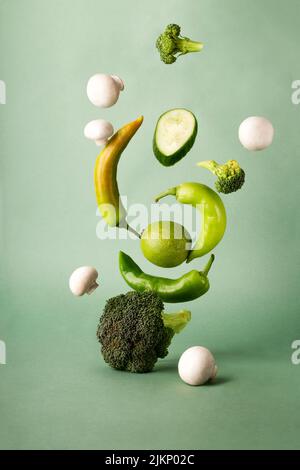 a vertical shot of flying vegetables on a green background Stock Photo