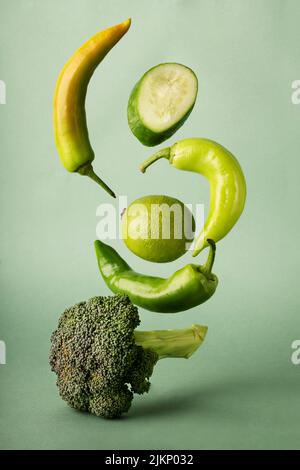 a vertical shot of flying vegetables on a green background Stock Photo