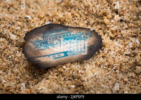 A closeup shot of a burnt piece of paper on a rocky sand Stock Photo