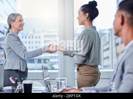 Growing success day by day with the right people. two businesswomen shaking hands during a meeting in an office. Stock Photo