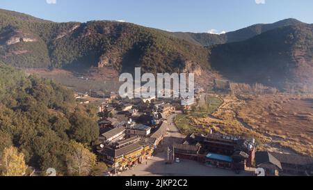 An aerial view of a small asian village with traditional buildings surrounded by forested mountains Stock Photo