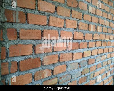 A closeup shot of the unfinished wall of red brick and cement in bright light Stock Photo