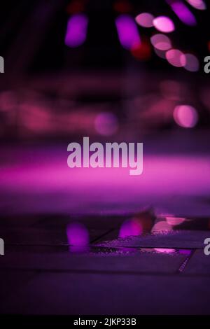 A closeup shot of a puddle on a pavement with blurred purple background Stock Photo
