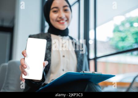 muslim woman showing blank mobile phone screen to camera Stock Photo