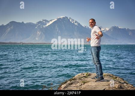 A male standing on the rock with mountains the sea on the background in Montreux, Switzerland Stock Photo