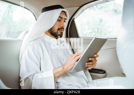 man wearing turban using a pad while sitting on his car Stock Photo