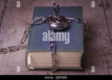 A closeup of a sectret book wrapped by chain with its padlock on a wooden table Stock Photo