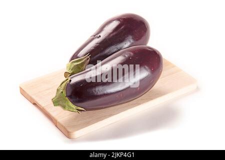 A closeup shot of eggplants on chopping board isolated on white background Stock Photo