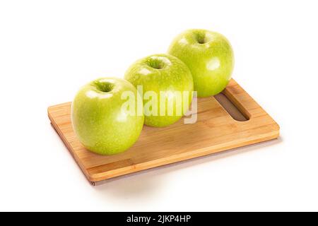 Three fresh green apples on a board isolated on a white background Stock Photo