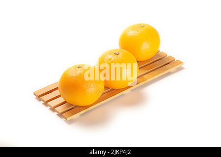 Three fresh oranges on a board isolated on a white background Stock Photo