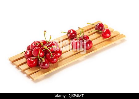 A closeup shot of cherries on a wooden board isolated on a white background Stock Photo