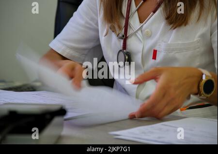 Midsection of doctor with stethoscope reading documents Stock Photo