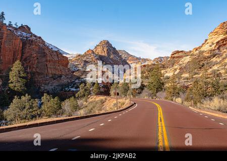 A paved highway through rocky mountain on a sunny day Stock Photo