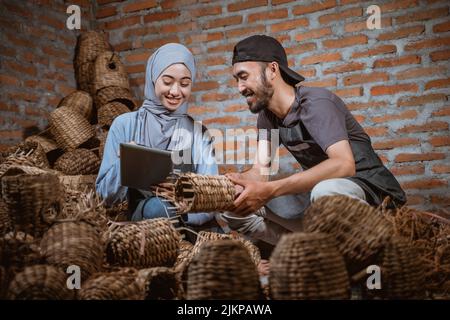 craftswoman in veil holding tablet and craftsman checking crafts Stock Photo