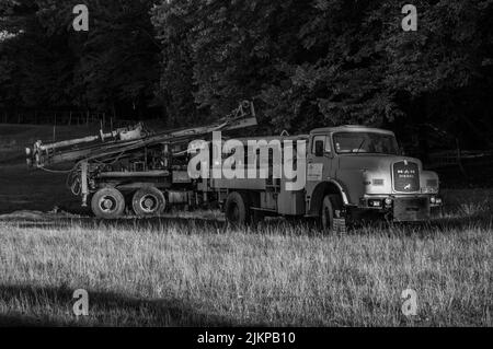 Two old blue trucks with crane abandoned in the field Stock Photo