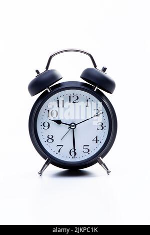 Black round metallic retro alarm clock isolated on white background. The clock shows daytime working hours. High quality photo Stock Photo