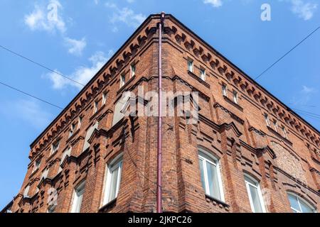 An old large brick building with a white sign for the name of a cafe or store. Brick building in the center of the city but against the blue sky. Stock Photo