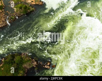 A top shot of foamy waves crashing on rocks covered in moss. Stock Photo