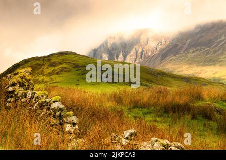 A view of a hill in the background of a mountain peak in the fog. Stock Photo