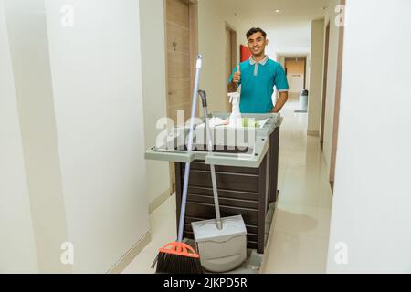 housekeepers with thumbs up pushing carts filled with cleaning supplies Stock Photo