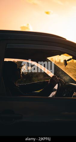 A closeup of a person smoking a cigarette and looking the sunset Stock Photo