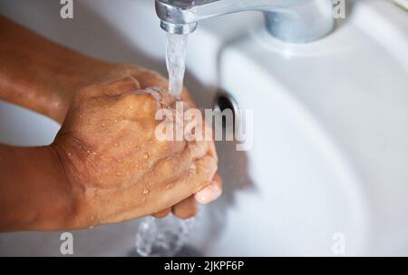 Making health a priority, one wash at time. an unrecognizable male washing his hands in a hand basin at home. Stock Photo