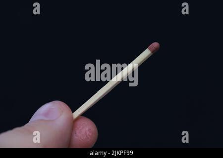 A closeup of a hand holding a match stick on a black background with copyspace Stock Photo