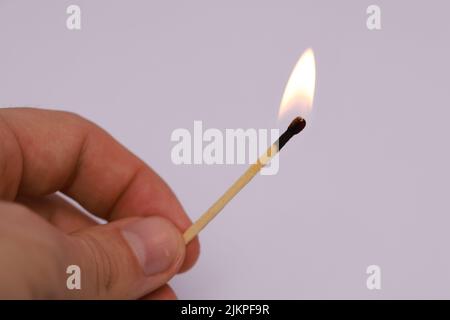 A closeup of a hand holding a burning match stick on a white background with copyspace Stock Photo
