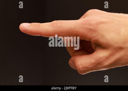 A closeup of an index finger pointing out isolated on a brown blurry background Stock Photo