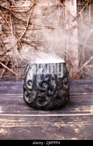 A closeup shot of smoke coming out from a ceramic cup on a wooden table Stock Photo