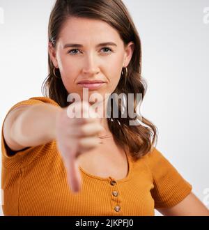 How I feel about Covid19. Studio shot of a young woman showing thumbs down against a white background. Stock Photo