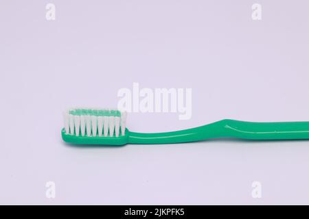 A closeup of a green toothbrush isolated on a pink background Stock Photo