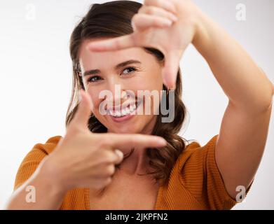 The camera loves you. Studio shot of a young woman making a frame with her hands against a white background. Stock Photo