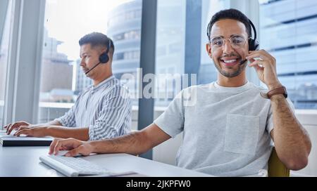 Were so happy to be of service. two business colleagues working together at their desks in their office. Stock Photo