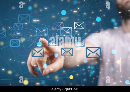 A closeup of a hand touching 3D rendered email symbols on a blue background, a network concept Stock Photo