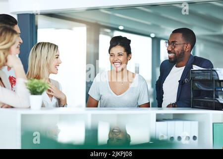 Group of business people talking and having a friendly discussion at work. Happy smiling employees telling funny stories. Diverse team laughing and Stock Photo