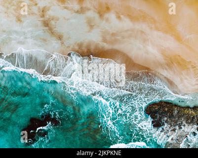 An aerial view of waves splashing on a sandy shore Stock Photo