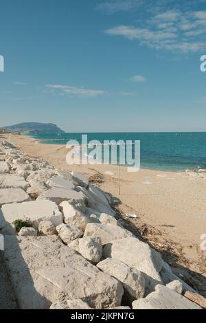 Vertical shot of rocks on a sandy shore under blue sky Stock Photo - Alamy