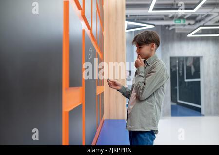 A school boy standing near lockers in the corridor Stock Photo