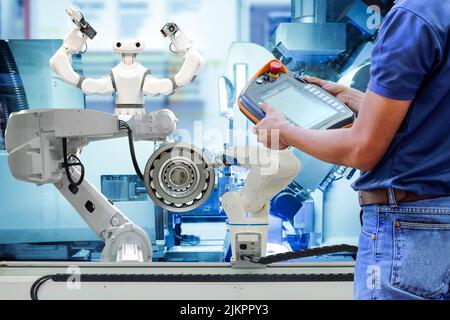 Close-up technician man who using wireless remote to setting program for control industrial robotics to work automation via line production Stock Photo