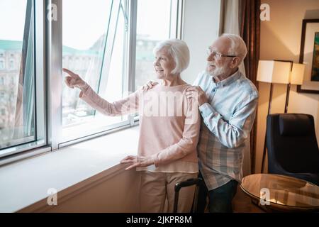 Senior couple standing near the window and looking happy Stock Photo
