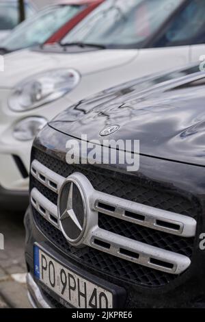 A vertical closeup of a parked Mercedes Benz car with the company logo. Stock Photo