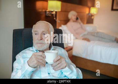 Senior bearded man having his morning coffee and looking thoughtful Stock Photo