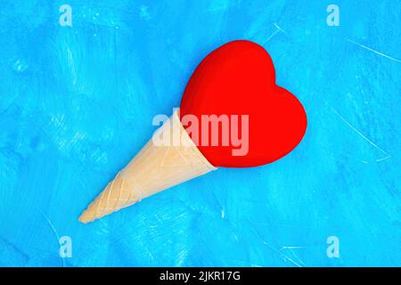Heart shaped waffle cone ice cream composition on blue background. Stock Photo